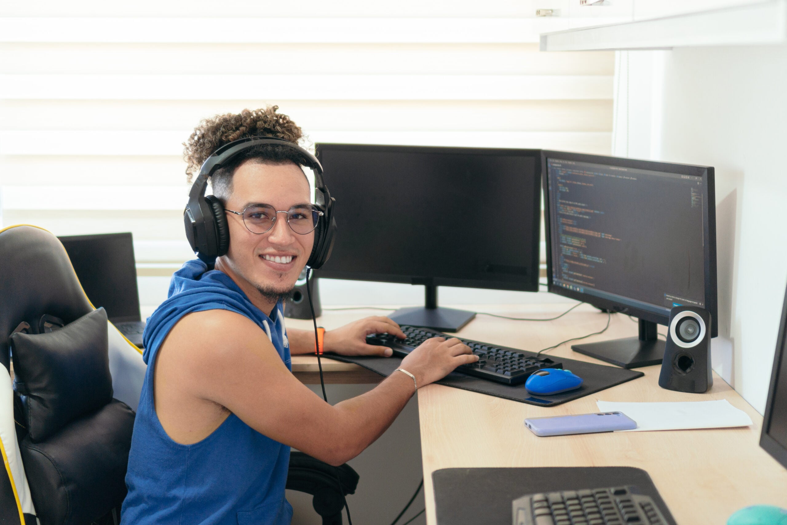 Young male programmer in casual clothes working on the computer at the table.