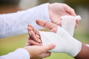 Sports, bandage and person with hand injury support, first aid emergency and strain after game, bandage a hand