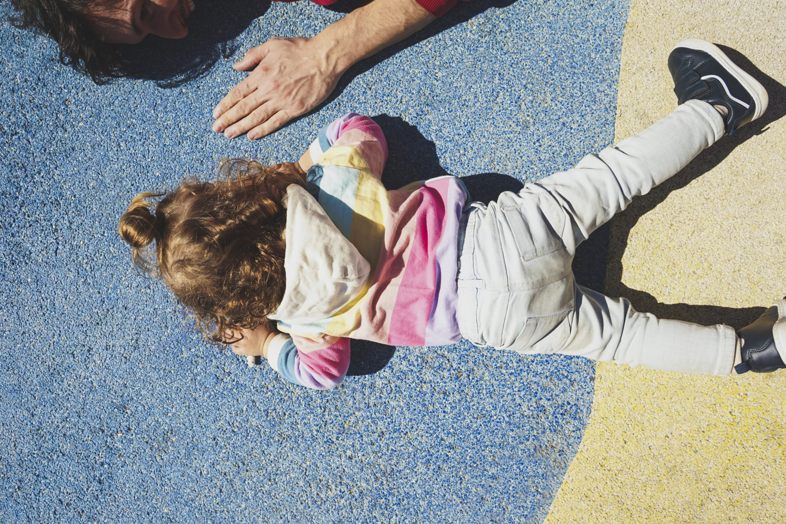 High view of a little girl and her father doing exercise outdoors
