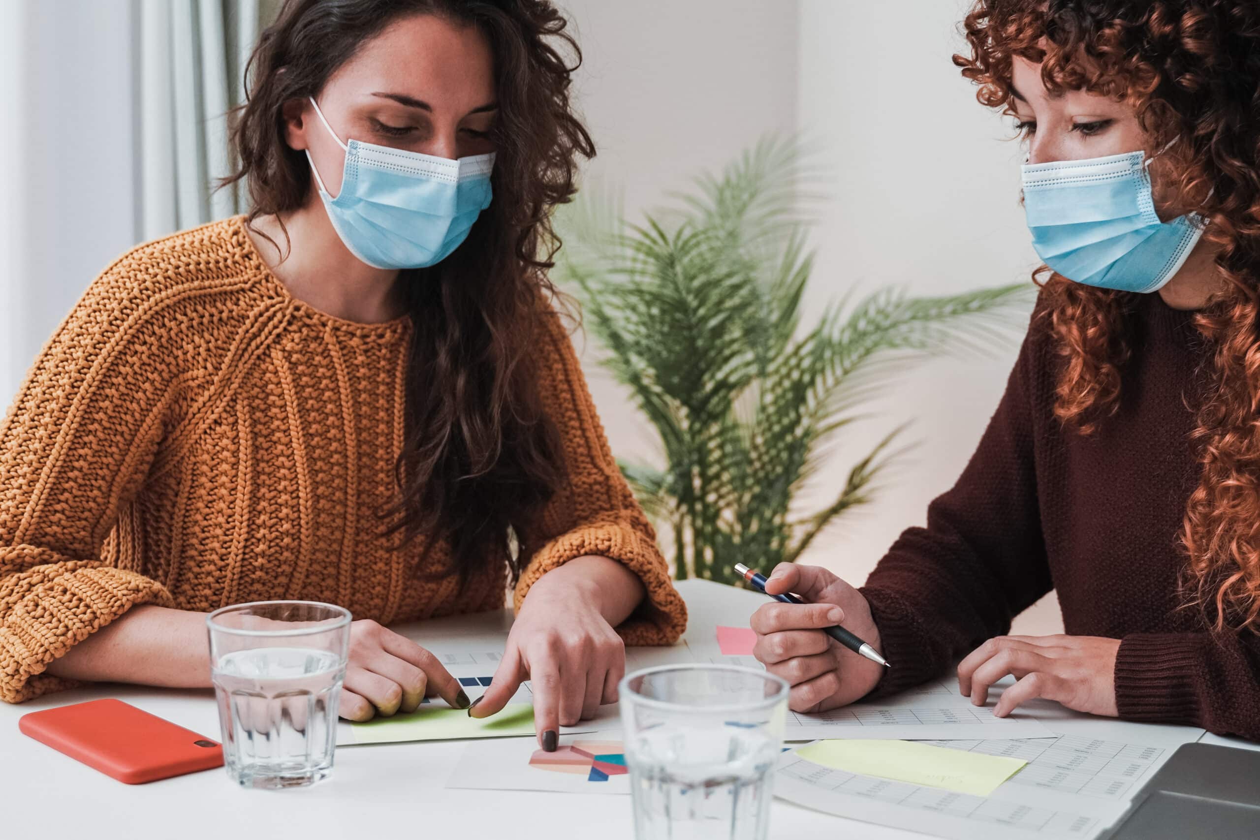 Young business women working inside modern office wearing safety masks during coronavirus outbreak