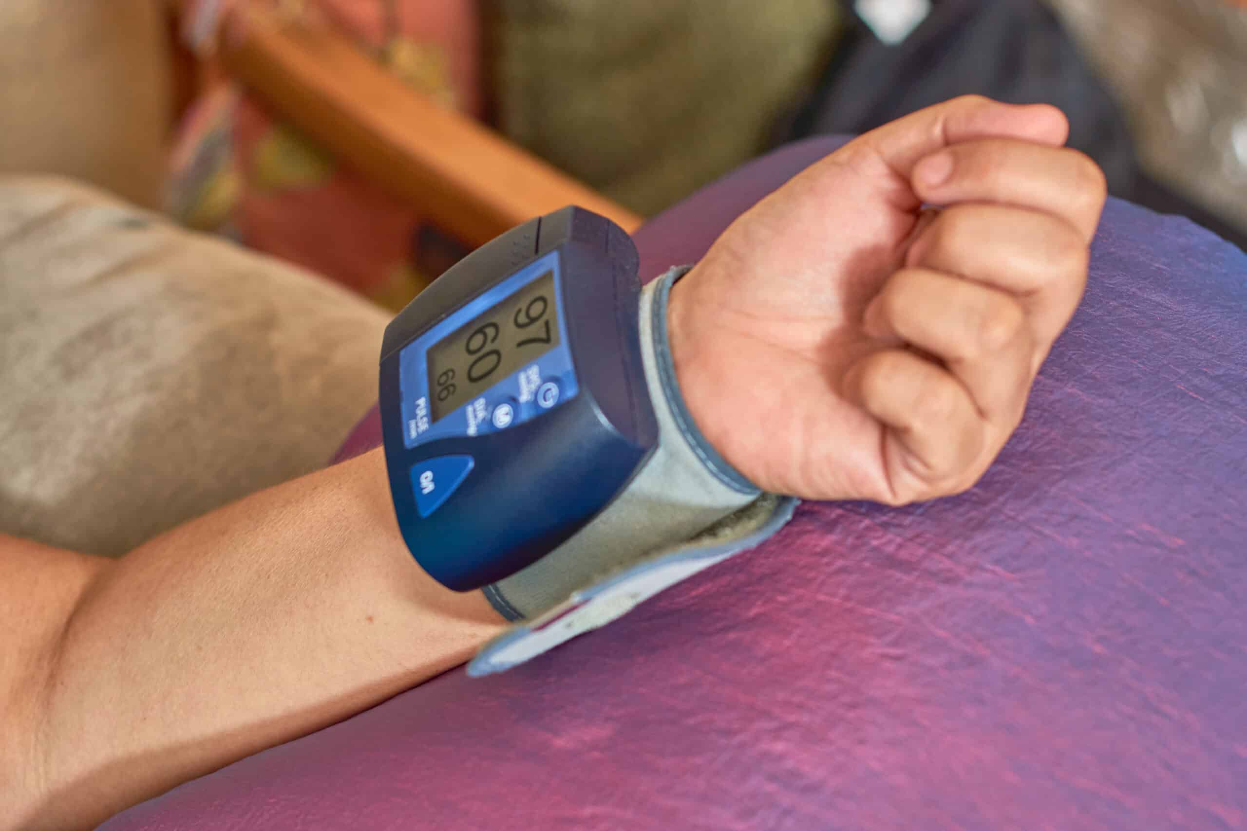 Hypertension concept and health care. Mature Latina woman measures her blood pressure with digital monitor from home.