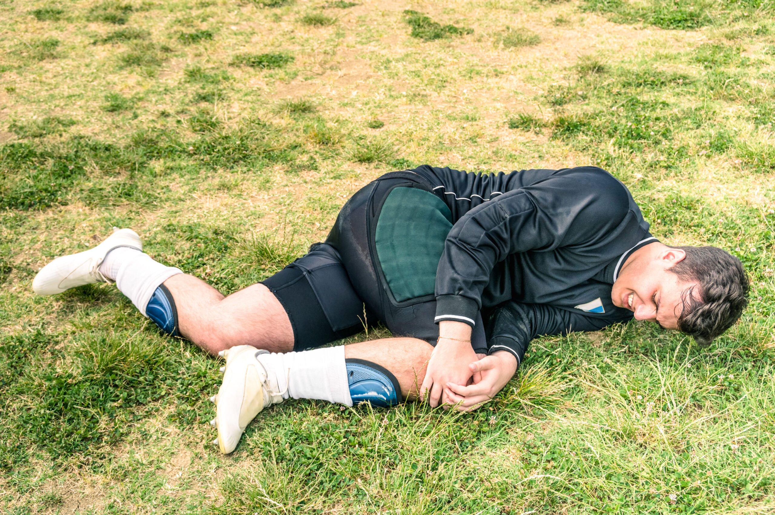 Soccer player injured during amateur football match - Concept of sport failure and physical accident