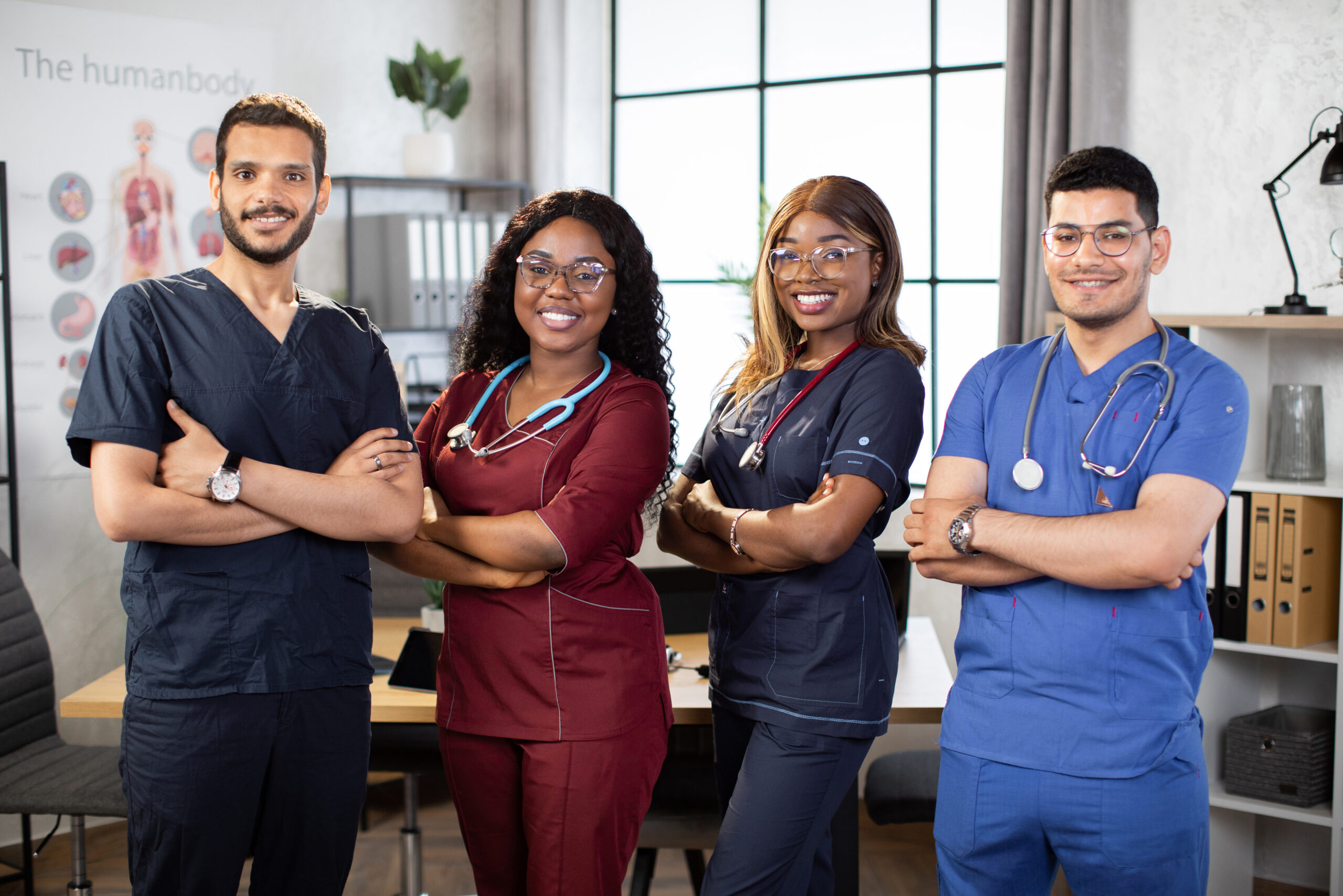 Diverse multiethnic cheerful medical team at work in hospital. Four multiracial colleagues healthcare workers, medical students. Mixed-races physicians and nurses looking at camera. Clinic team.
