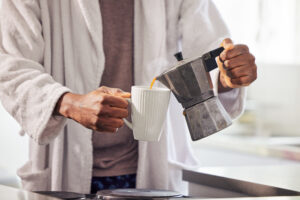 Shot of an unrecognizable man pouring coffee into a cup at home. coffee making