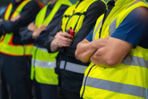 group of men in yellow safety vests stand together. They are all wearing the same type of vest and are all wearing the same color. thank a first responder day