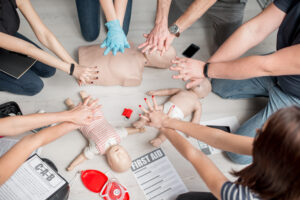 Group of people learning how to make first aid heart compressions with dummies during the training indoors world first aid day