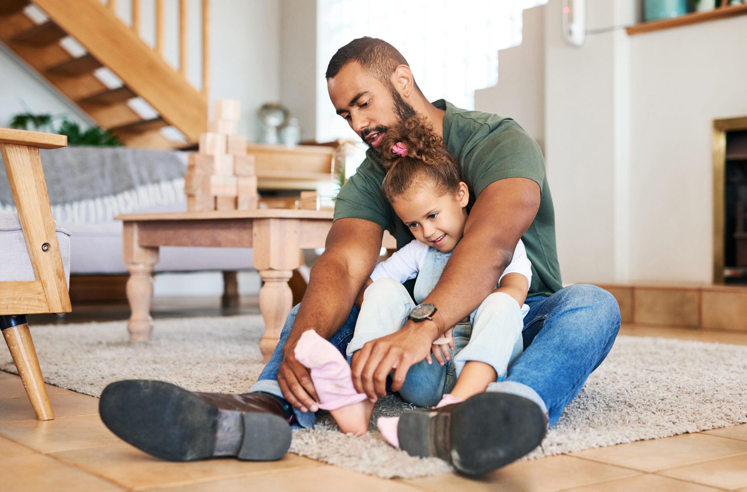 Shot of a father helping his daughter put socks on her feet at home. fathers' day