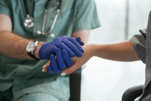 Blue gloves. Two doctors are holding hands indoors. World Patient Safety Day 2026