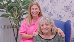 Caregiver woman smiling with senior woman receiving assistance in a nursing home National Carers Week 2026