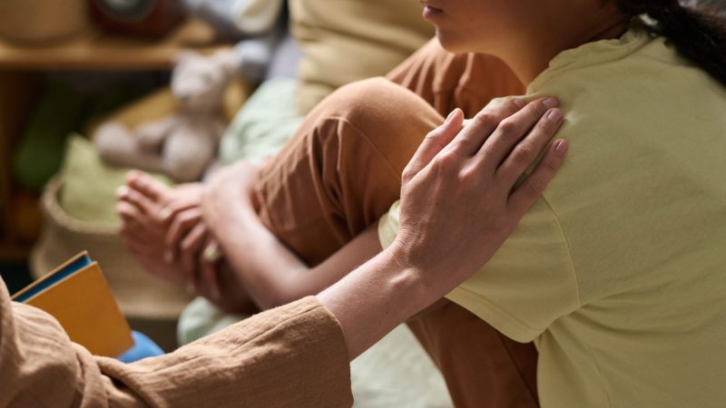 Close-up of psychologist supporting girl in difficult situation during their conversation. Supporting National Child Protection Week 2026