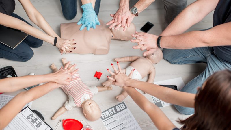 Group of people learning how to make first aid heart compressions with dummies during the training indoors world first aid day