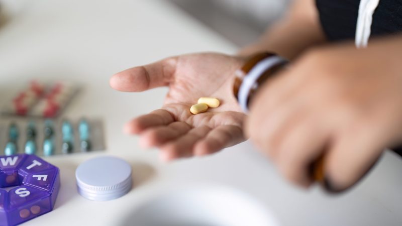 Sick illness woman hold two pill on hand pouring capsules from medication bottle take painkiller supplement medicine. Healthcare, headache, treatment, therapy concept. beta blockers