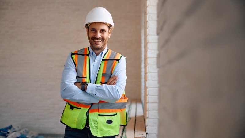 Confident building contractor at construction site looking at camera. Tradies National Health Month.