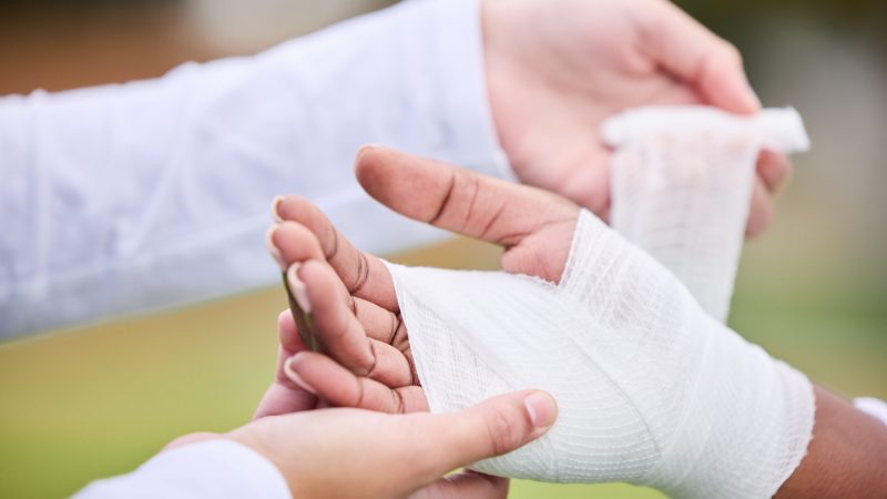 Sports, bandage and person with hand injury support, first aid emergency and strain after game, bandage a hand