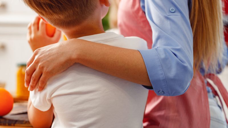 Woman in apron hugging her son, back view close up Child Protection Refresher Training